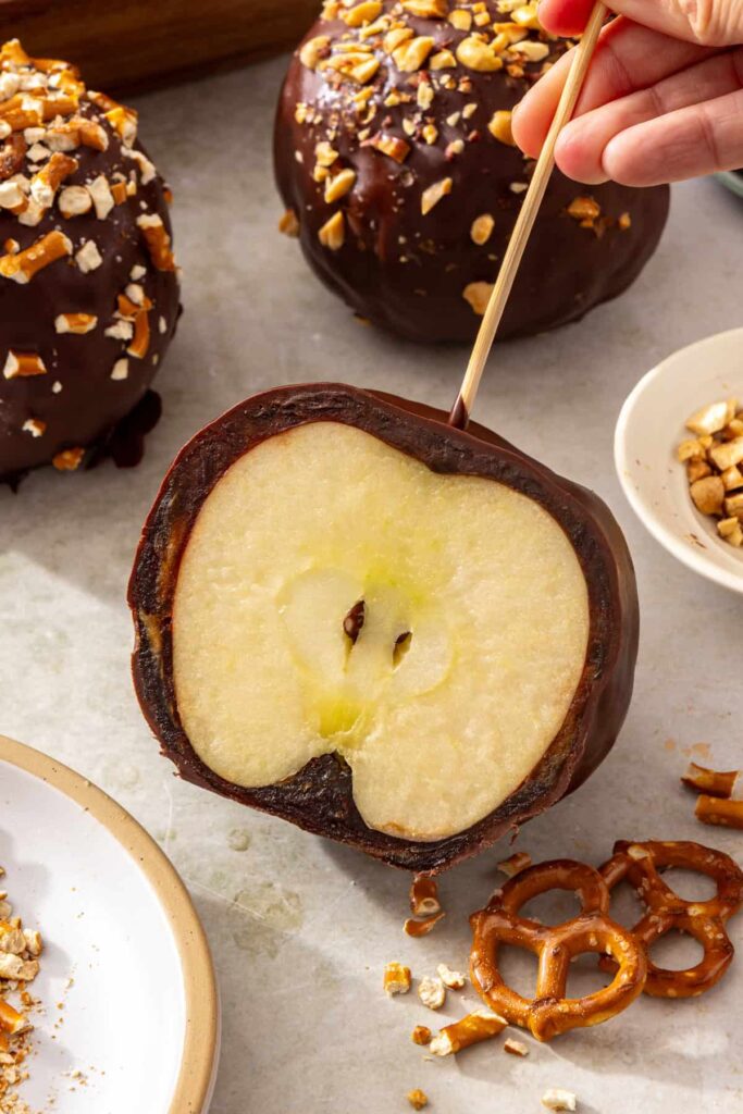 Close-up of a chocolate-covered date caramel apple sliced in half showing the date caramel layer and crisp apple inside