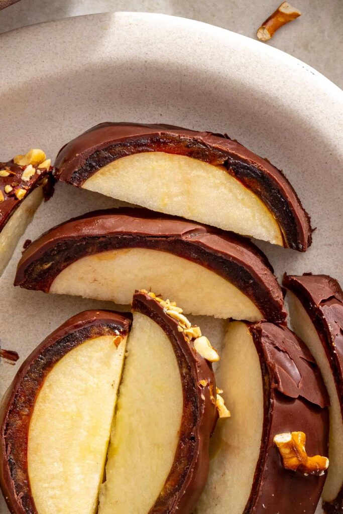 Overhead view of sliced chocolate-covered date caramel apples on a serving plate