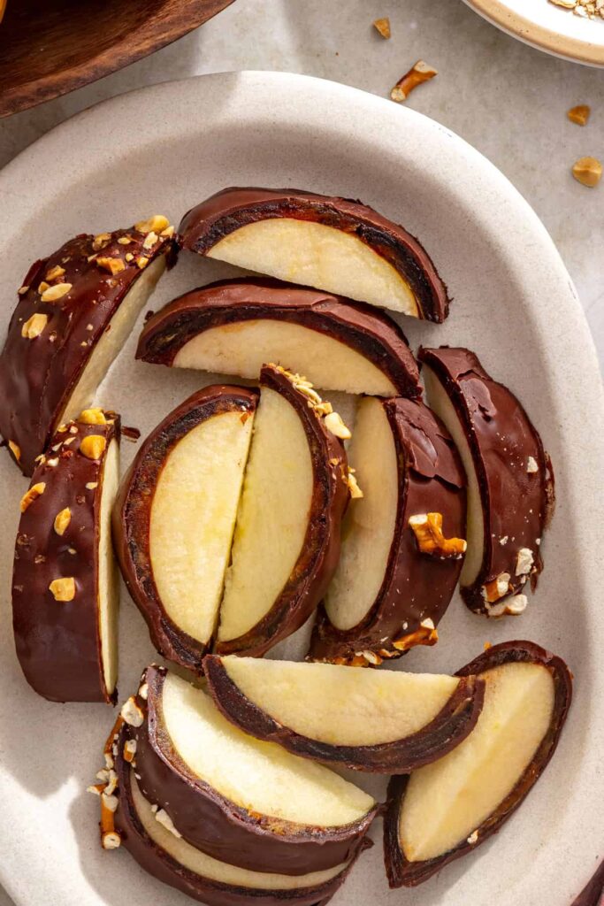 Sliced chocolate date caramel apples arranged on a serving plate