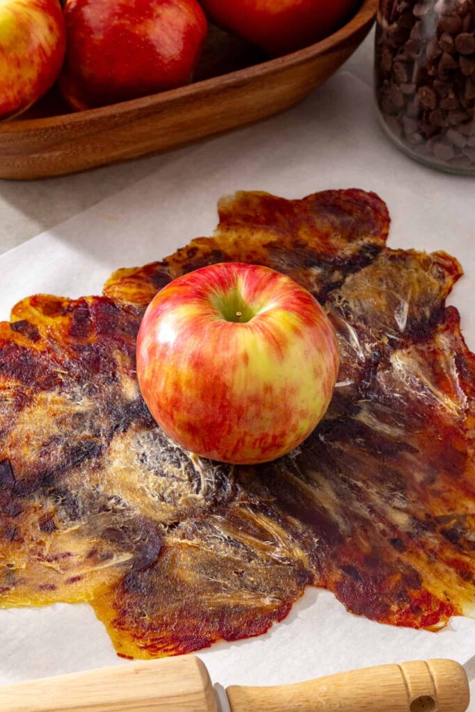 apple placed in the center of a paper-thin square of rolled dates for date caramel apple