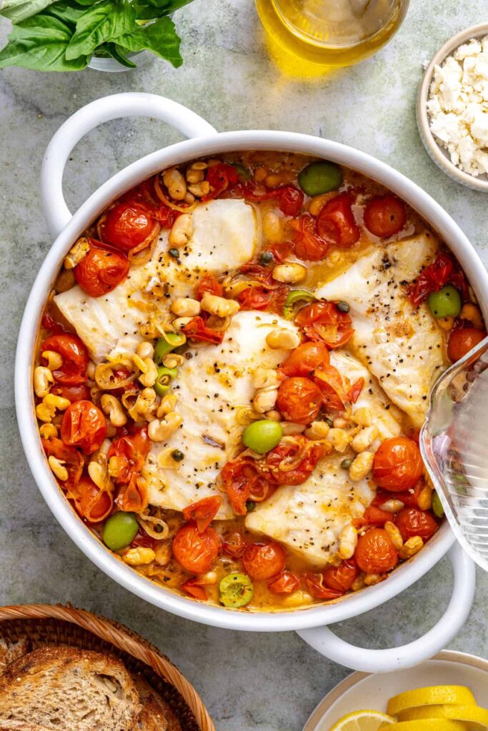 Fresh lemon juice squeezed over baked cod with tomatoes and white beans before garnishing with feta and basil.