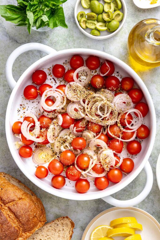 Cherry tomatoes, sliced shallot, garlic, olive oil, oregano, and red pepper flakes in an oven-safe skillet before roasting.