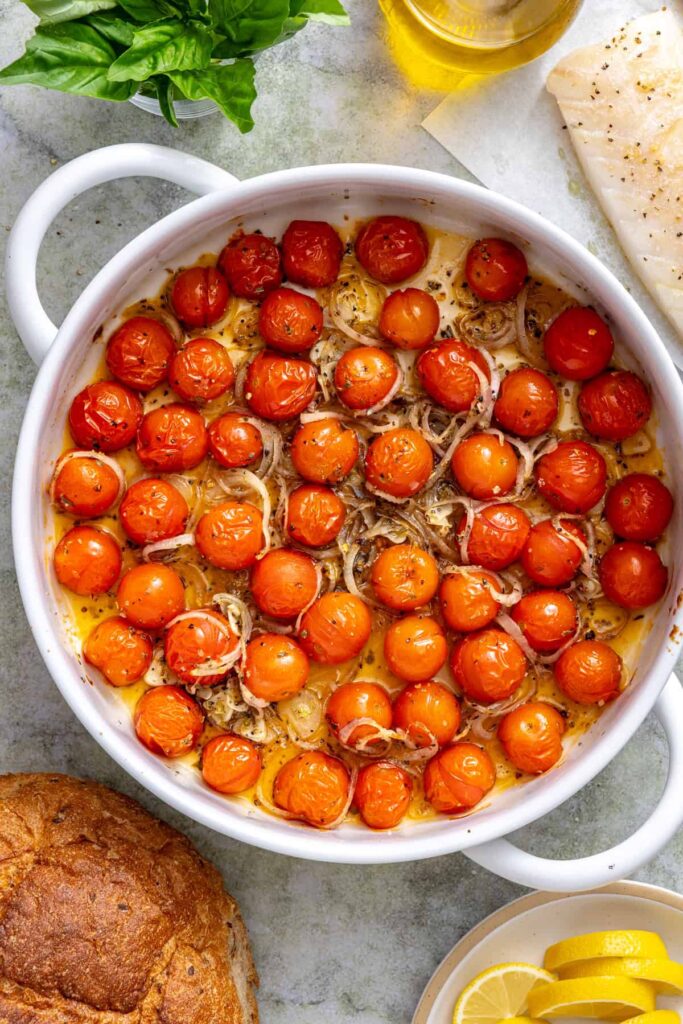Cherry tomatoes blistered and softened after roasting in an oven-safe skillet with garlic and shallot.