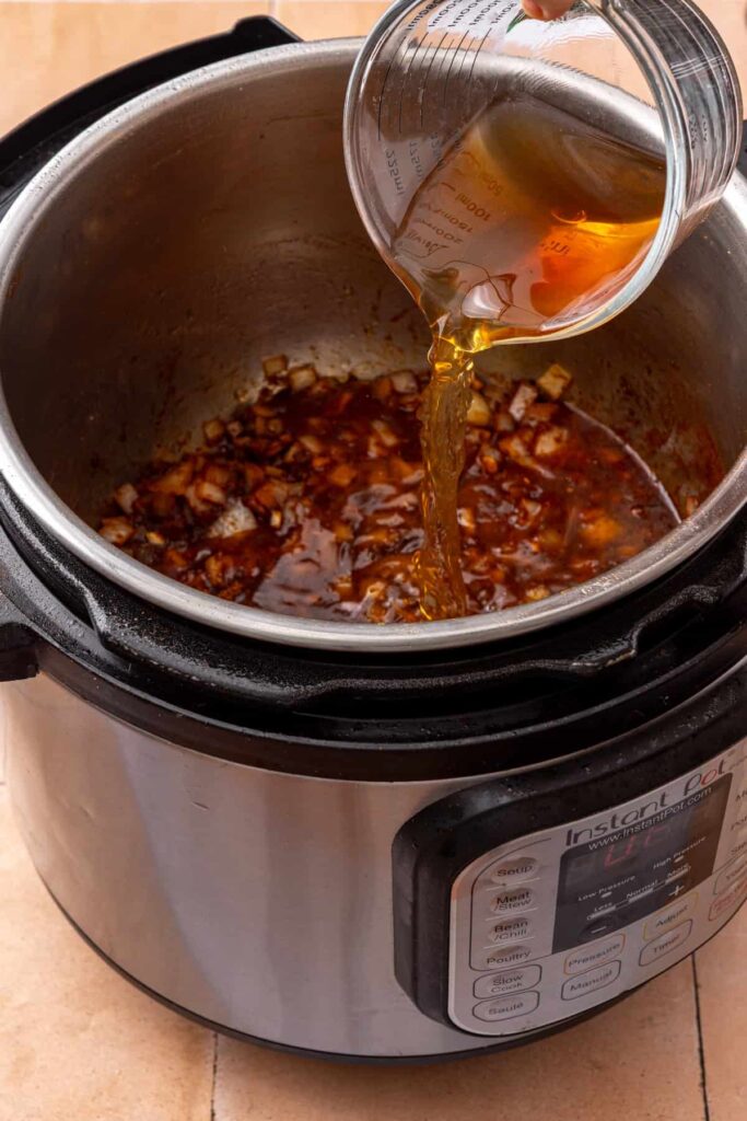 Beef bone broth added to the seasoned onion mixture in the Instant Pot for taco beef.
