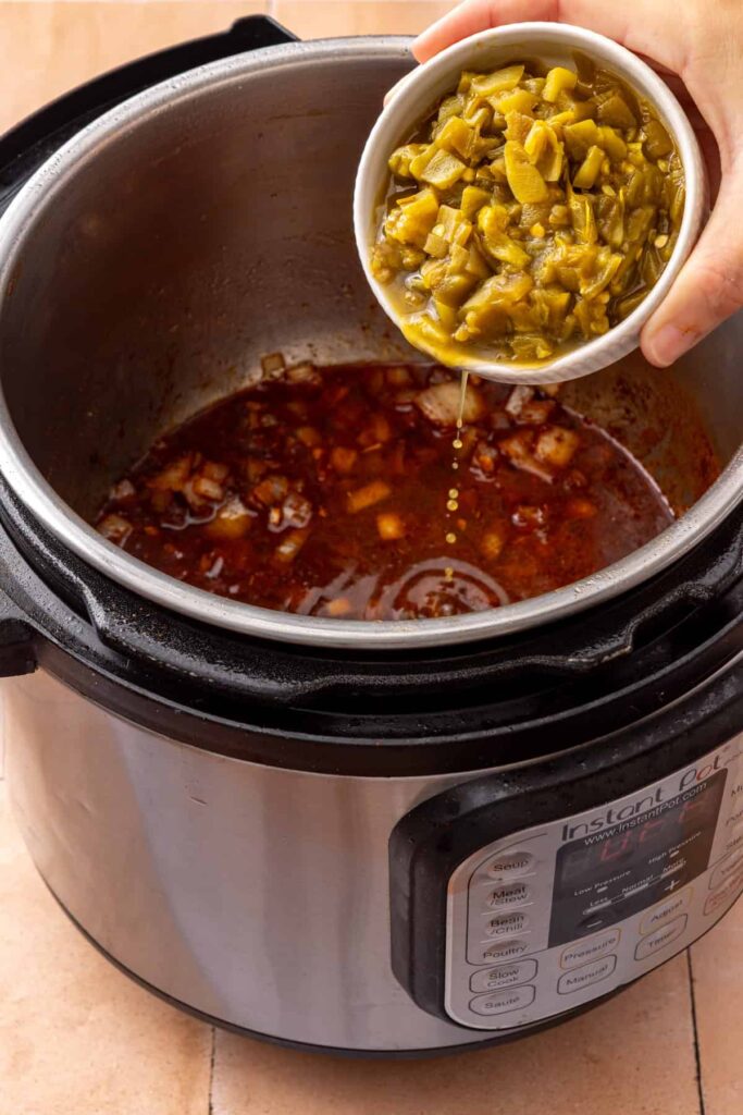adding diced green chiles into the Instant Pot for beef taco sweet potatoes