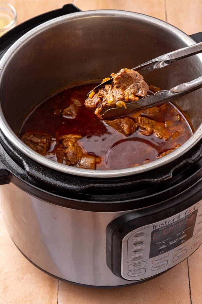 Shredded beef stirred into reduced taco cooking juices in the Instant Pot for juicy beef taco filling.