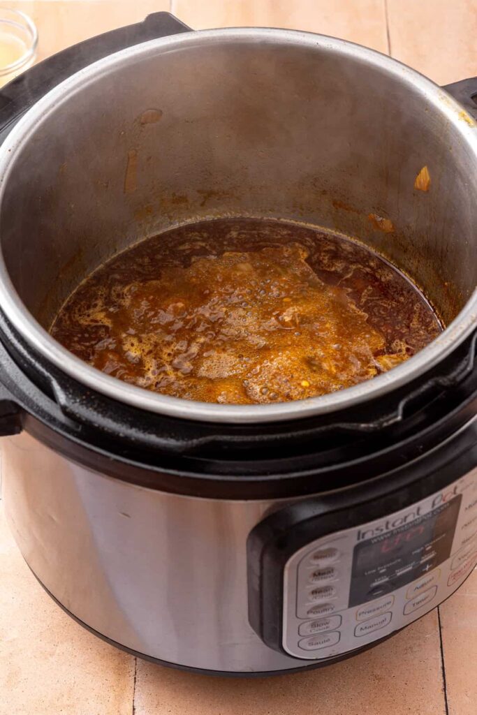 Tender shredded beef coated in seasoned broth after returning it to the Instant Pot.