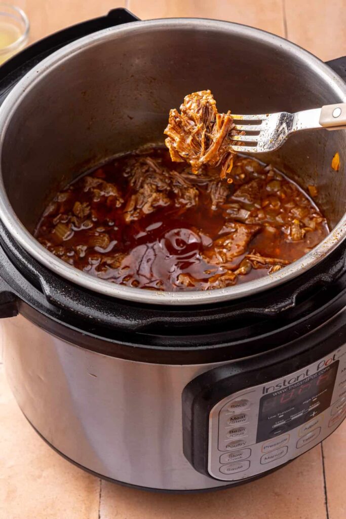 fork lifting up shredded beef from the Instant Pot