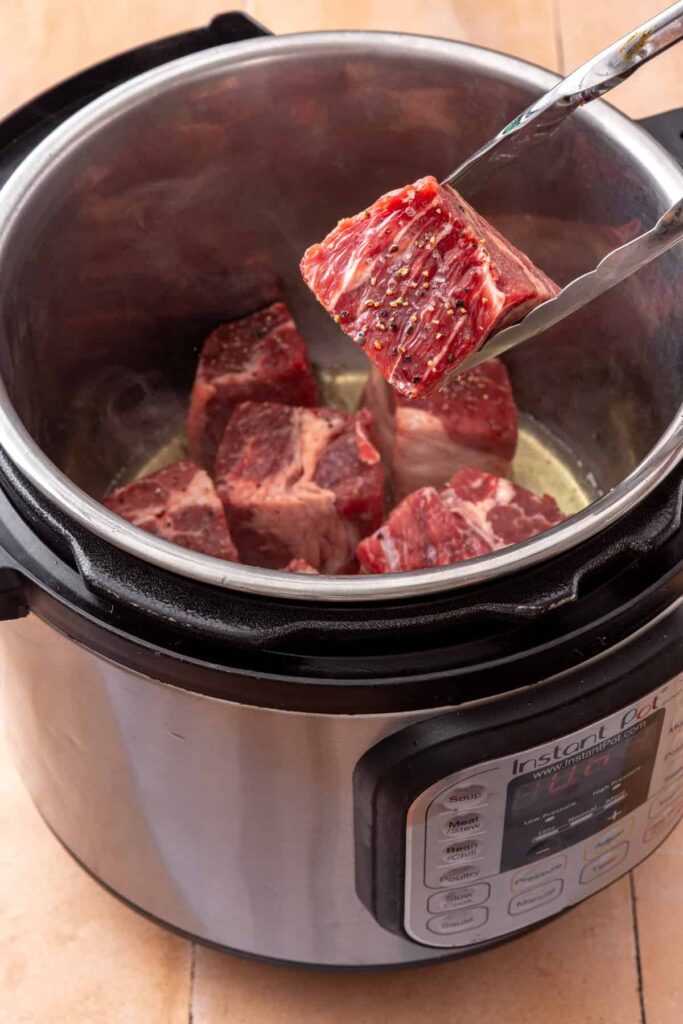 Beef chuck roast searing in avocado oil in the Instant Pot before pressure cooking.