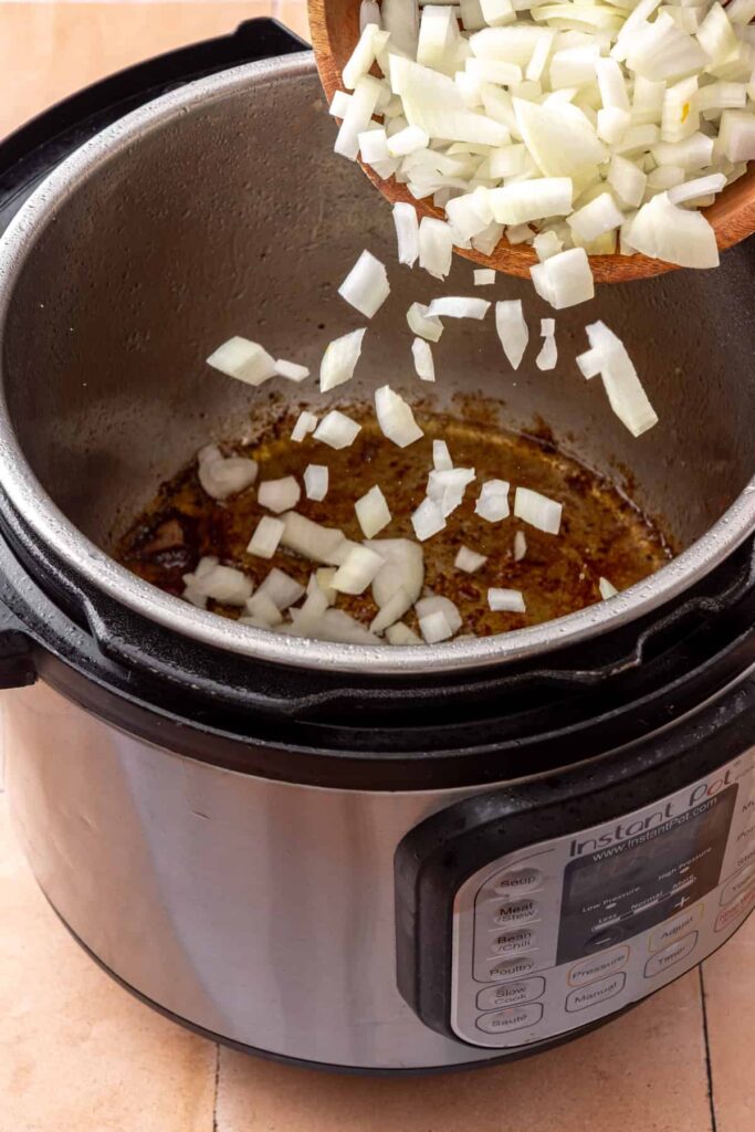 Diced yellow onion sautéing in the Instant Pot after the beef is seared.