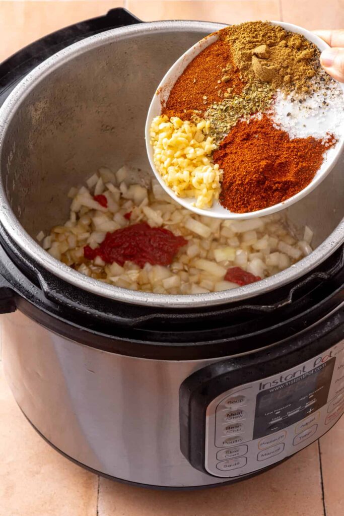 Chili powder, cumin, smoked paprika, oregano, garlic, and tomato paste stirred into the onion mixture for shredded beef.