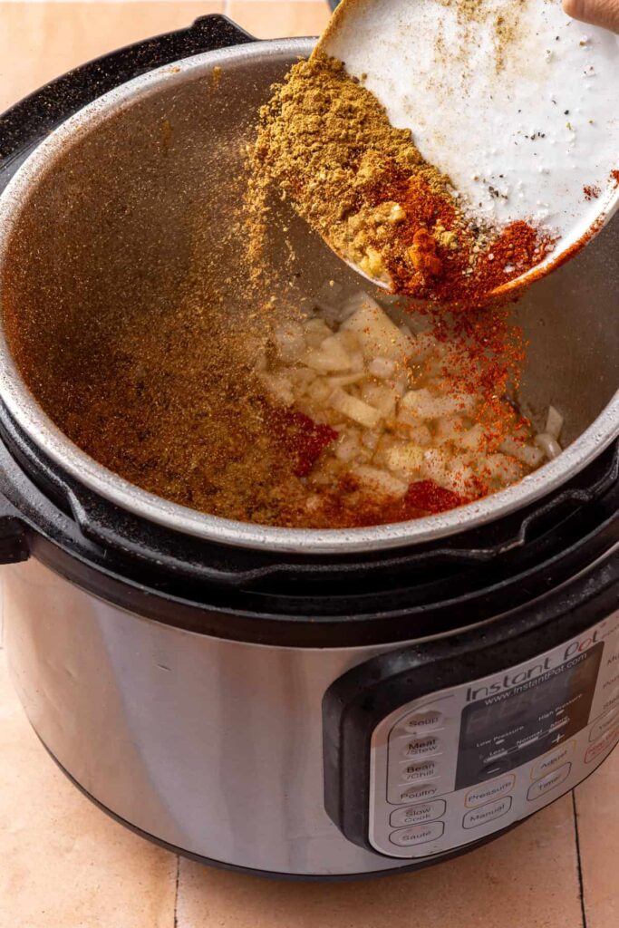 Minced garlic, tomato paste, and taco spices cooking with sautéed onion in the Instant Pot.