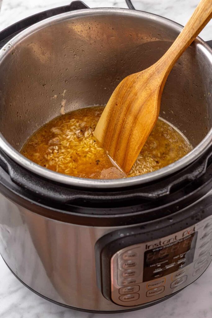stirring rice being cooked in chicken broth and lemon zest in the Instant Pot