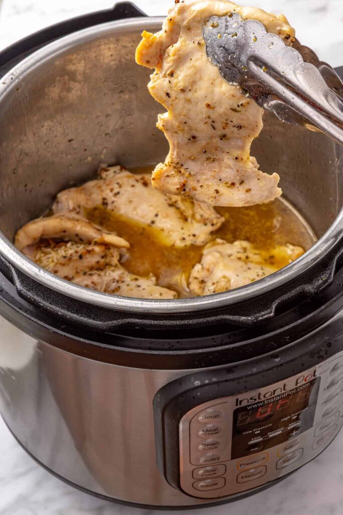 Seared chicken thighs nestled on top of lemon-seasoned rice in the Instant Pot before pressure cooking.