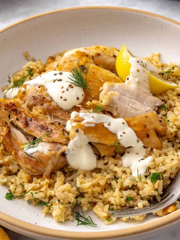 Instant Pot Greek lemon chicken and rice topped with creamy lemon yogurt sauce and fresh herbs.