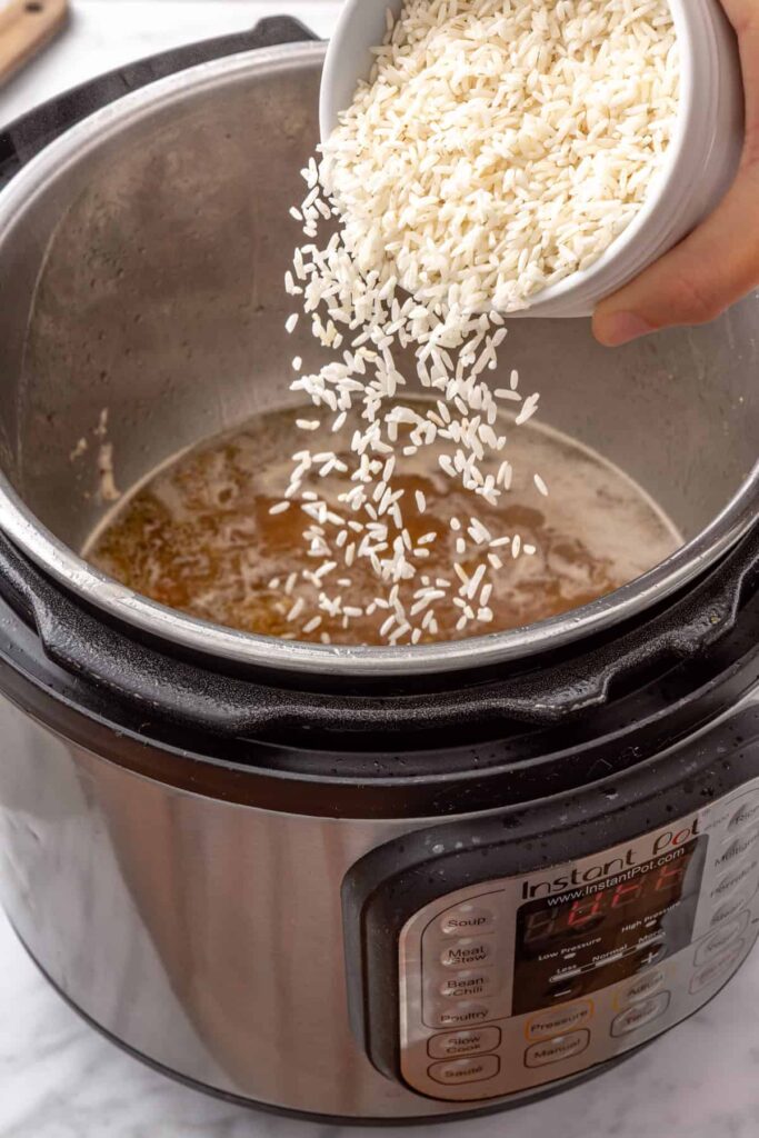 Rinsed white rice and fresh lemon zest stirred into chicken broth in the Instant Pot.