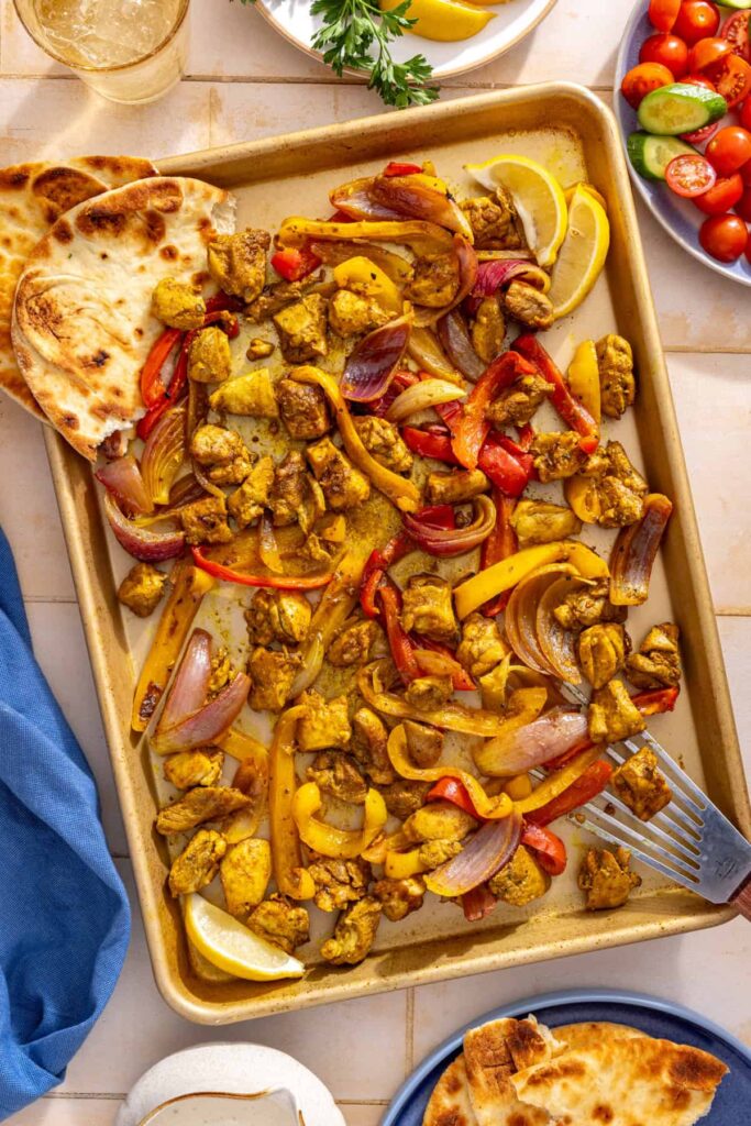 Sheet pan chicken shawarma with roasted bell peppers and red onion fresh from the oven.