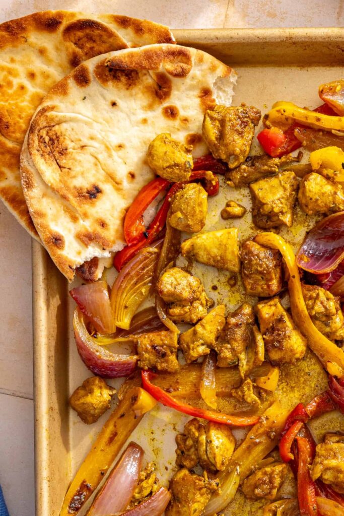 Roasted chicken and vegetables for chicken shawarma bowls, served family-style with pita bread.