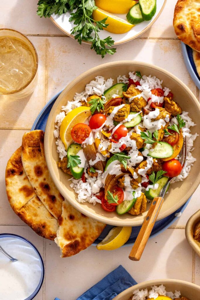 Sheet pan chicken shawarma served over basmati rice with fresh cucumber, cherry tomatoes, and feta garlic dressing.
