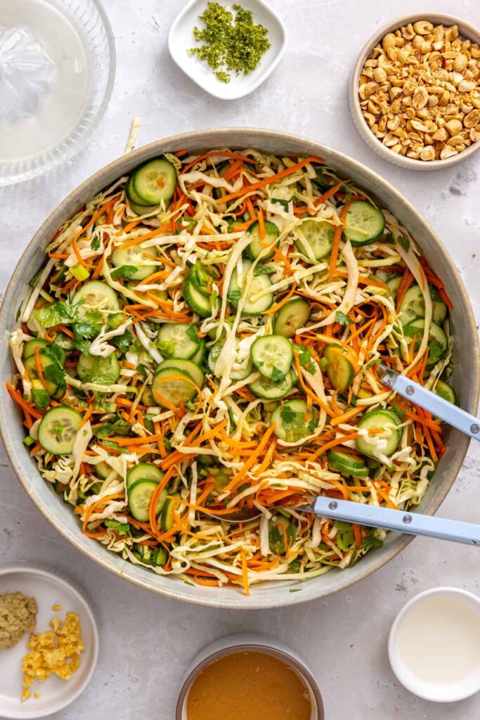 Tossing shredded cabbage, carrots, cucumber, and fresh herbs together to prepare the crunchy wrap slaw.