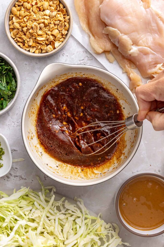 Whisking the lime, coconut aminos, sesame oil, garlic, and ginger together to make chicken marinade.
