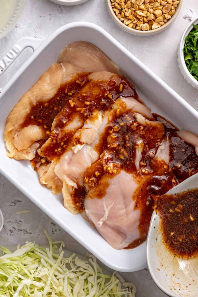Boneless chicken breasts added to the lime and garlic marinade for Thai peanut chicken wraps.