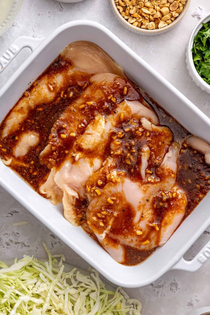 Boneless chicken breasts added to marinade for Thai peanut chicken wraps.